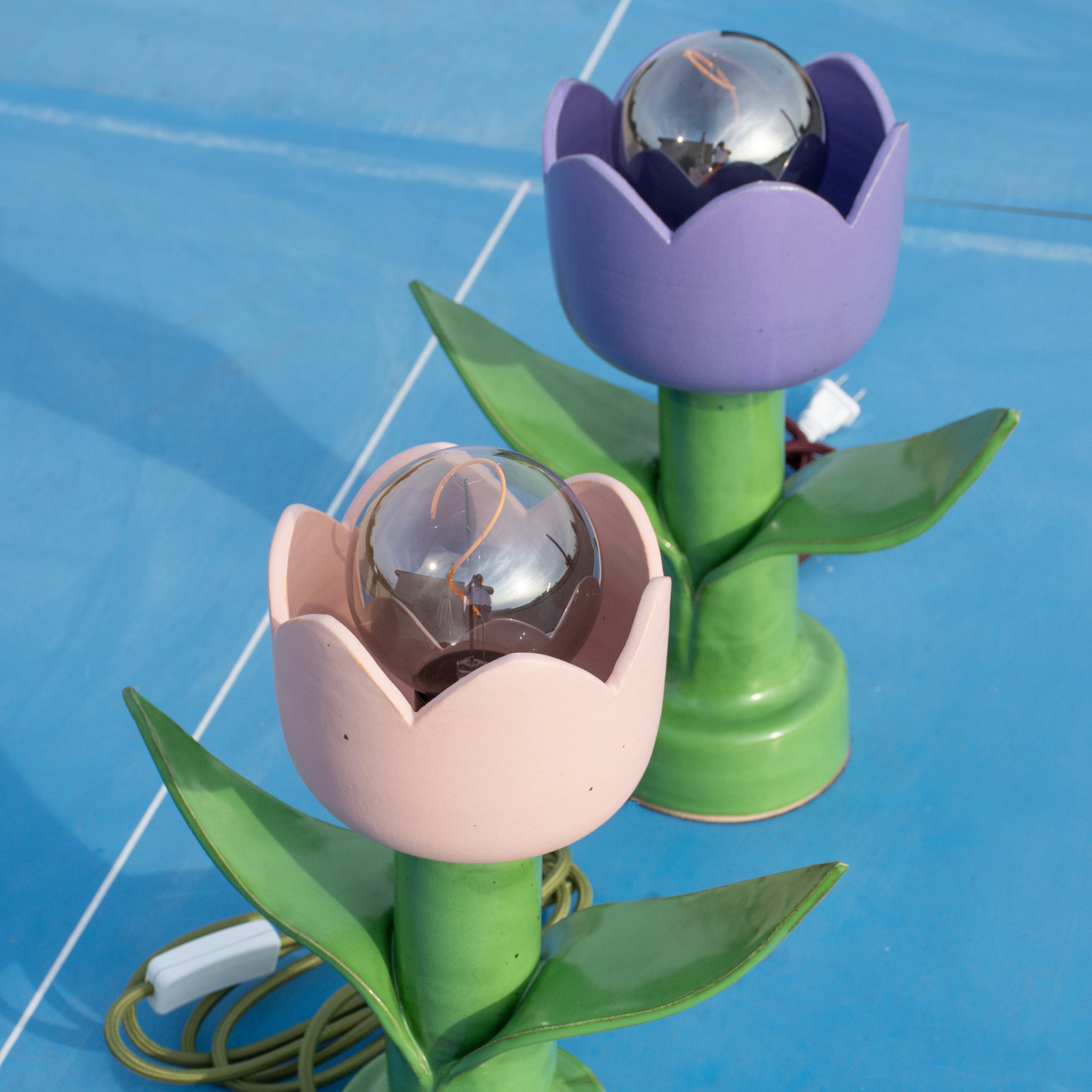 Two lights in the shape of tulips sitting on a blue background.