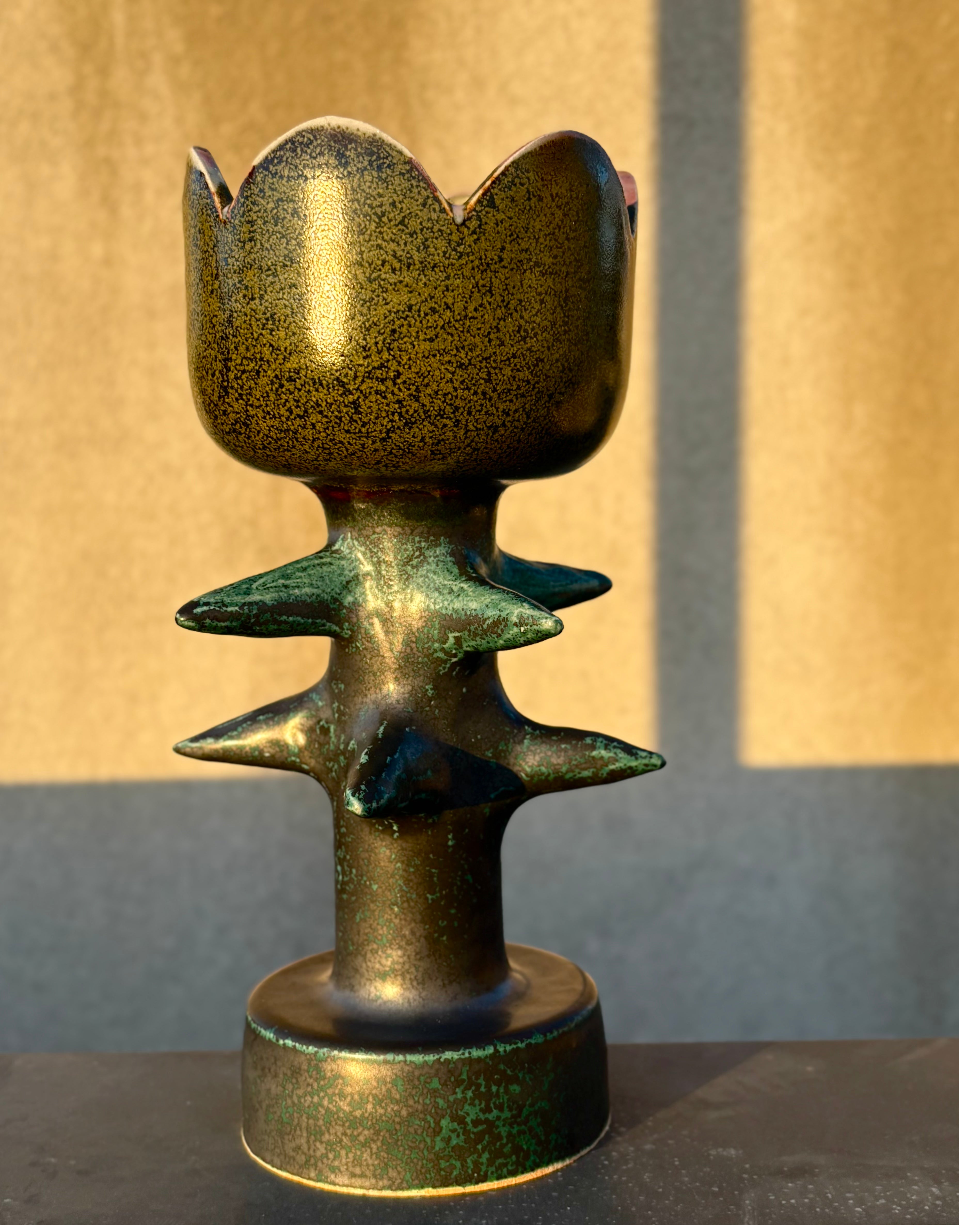 Ceramic tulip lamp with bronzed looking glaze, sitting on a table in golden hour light.
